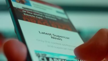 Smartphone in hand, looking for information about the super car.