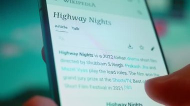 Smartphone in hand, looking for information about night clouds.