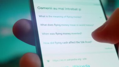 Smartphone in hand, looking for information about flying money.