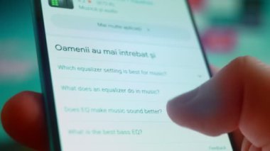 Smartphone in hand, looking for information about music equalizer.