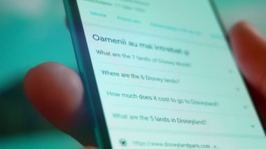 Smartphone in hand, Im looking for information about Disneyland on the Internet.