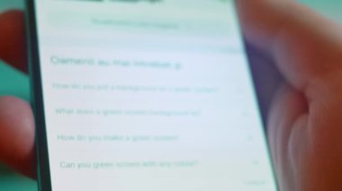 Smartphone in hand, looking for information about green screen background.