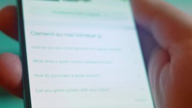 Smartphone in hand, looking for information about green screen background.