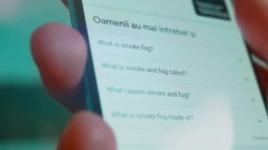 Smartphone in hand, looking for information about smoke fog.