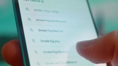 Smartphone in hand, looking for information about smoke fog.