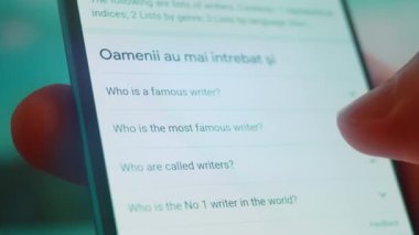 Smartphone in hand, looking for information about writers.
