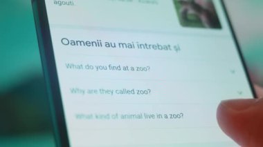 Smartphone in hand, looking for information about zoo animals.