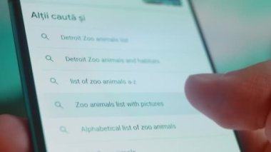 Smartphone in hand, looking for information about zoo animals.