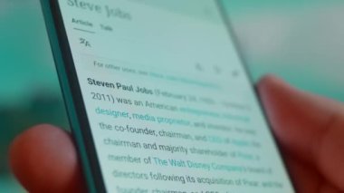 Smartphone in hand, looking for information about steve jobs.