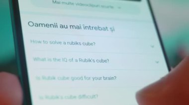 Smartphone in hand, looking for information about rubik cube.