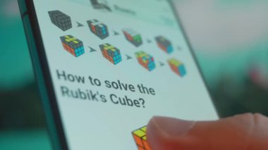 Smartphone in hand, looking for information about rubik cube.