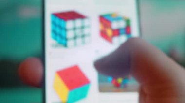 Smartphone in hand, looking for information about rubik cube.