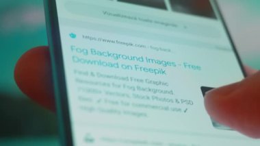 Smartphone in hand, looking for information about fog background.