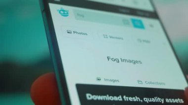Smartphone in hand, looking for information about fog background.