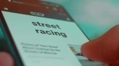 Smartphone in hand, looking for information about street racing.