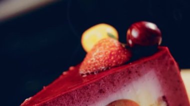 Çilekli, beyaz ve kırmızı kirazlı bir dilim pasta. Pastanın özel bir kubbesi var. Makro ve kaydırma atışı. Arka planda bir retro atmosfer var..