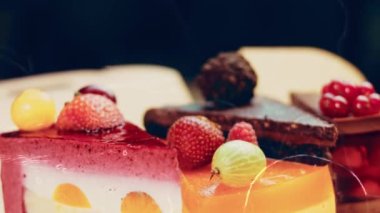 Açık bir kutuda birkaç dilim beyaz ve kırmızı çilekli ve kirazlı pasta ve çikolata. Makro ve kaydırma atışı. Arka planda bir retro atmosfer var..