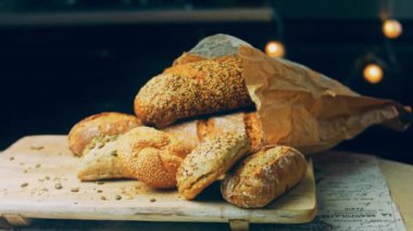 Ahşap masada farklı türde taze ekmek. Kahverengi arka planda münferit bir ekmek çeşidi. Kaydırıcı atışı.