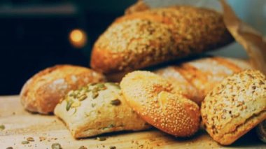 Ahşap masada farklı türde taze ekmek. Kahverengi arka planda münferit bir ekmek çeşidi. Kaydırıcı atışı.