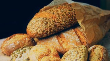 Ahşap masada farklı türde taze ekmek. Kahverengi arka planda münferit bir ekmek çeşidi. Kaydırıcı atışı.