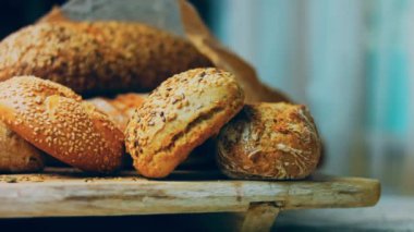 Ahşap masada farklı türde taze ekmek. Kahverengi arka planda münferit bir ekmek çeşidi. Kaydırıcı atışı.