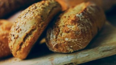 Ahşap masada farklı türde taze ekmek. Kahverengi arka planda münferit bir ekmek çeşidi. Kaydırıcı atışı.