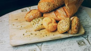 Ahşap masada farklı türde taze ekmek. Kahverengi arka planda münferit bir ekmek çeşidi. Kaydırıcı atışı.