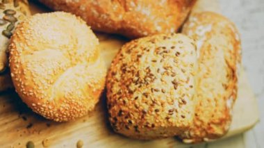 Ahşap masada farklı türde taze ekmek. Kahverengi arka planda münferit bir ekmek çeşidi. Kaydırıcı atışı.