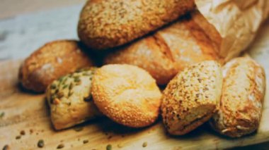 Ahşap masada farklı türde taze ekmek. Kahverengi arka planda münferit bir ekmek çeşidi. Kaydırıcı atışı.