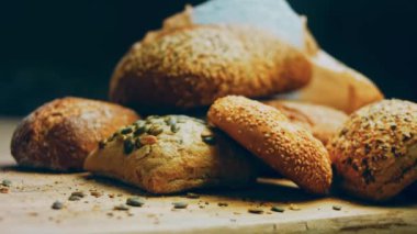 Ahşap masada farklı türde taze ekmek. Kahverengi arka planda münferit bir ekmek çeşidi. Kaydırıcı atışı.