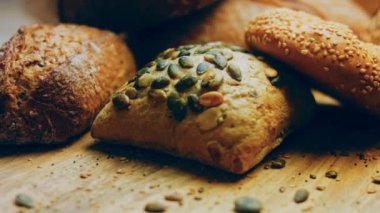 Ahşap masada farklı türde taze ekmek. Kahverengi arka planda münferit bir ekmek çeşidi. Kaydırıcı atışı.