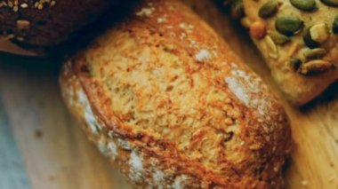 Ahşap masada farklı türde taze ekmek. Kahverengi arka planda münferit bir ekmek çeşidi. Kaydırıcı atışı.