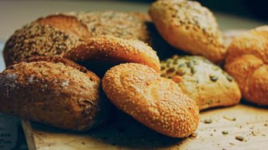 Ahşap masada farklı türde taze ekmek. Kahverengi arka planda münferit bir ekmek çeşidi. Kaydırıcı atışı.