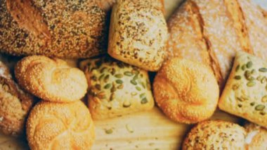 Ahşap masada farklı türde taze ekmek. Kahverengi arka planda münferit bir ekmek çeşidi. Kaydırıcı atışı.