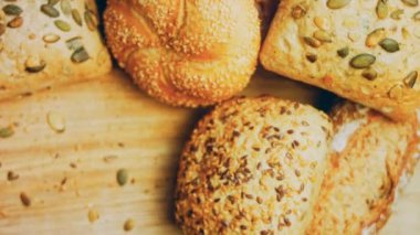 Ahşap masada farklı türde taze ekmek. Kahverengi arka planda münferit bir ekmek çeşidi. Kaydırıcı atışı.