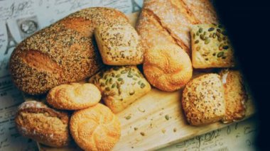 Ahşap masada farklı türde taze ekmek. Kahverengi arka planda münferit bir ekmek çeşidi. Kaydırıcı atışı.