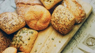 Ahşap masada farklı türde taze ekmek. Kahverengi arka planda münferit bir ekmek çeşidi. Kaydırıcı atışı.