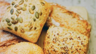 Ahşap masada farklı türde taze ekmek. Kahverengi arka planda münferit bir ekmek çeşidi. Kaydırıcı atışı.