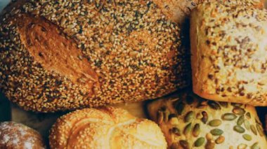 Ahşap masada farklı türde taze ekmek. Kahverengi arka planda münferit bir ekmek çeşidi. Kaydırıcı atışı.