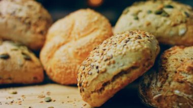 Ahşap masada farklı türde taze ekmek. Kahverengi arka planda münferit bir ekmek çeşidi. Kaydırıcı atışı.