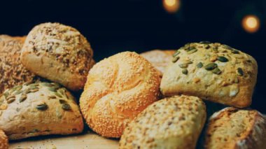 Ahşap masada farklı türde taze ekmek. Kahverengi arka planda münferit bir ekmek çeşidi. Kaydırıcı atışı.