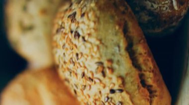 Ahşap masada farklı türde taze ekmek. Kahverengi arka planda münferit bir ekmek çeşidi. Kaydırıcı atışı.