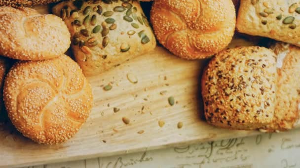 木製のテーブルの上に新鮮なパンの異なる種類 茶色の背景にパンの隔離された品揃え スライダーシュート — ストック動画