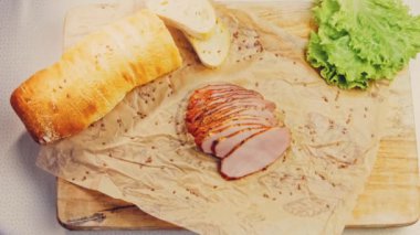 Fransız ekmeğiyle dilimlenmiş domuz filetosu. Sosis retro-stil yemek tepsisinde ve yemek kağıdında. Yavaş çekim kaydırağın üzerinde. Taze marul yaprakları da kullanıyoruz..