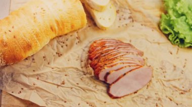 Fransız ekmeğiyle dilimlenmiş domuz filetosu. Sosis retro-stil yemek tepsisinde ve yemek kağıdında. Yavaş çekim kaydırağın üzerinde. Taze marul yaprakları da kullanıyoruz..