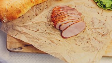 Fransız ekmeğiyle dilimlenmiş domuz filetosu. Sosis retro-stil yemek tepsisinde ve yemek kağıdında. Yavaş çekim kaydırağın üzerinde. Taze marul yaprakları da kullanıyoruz..