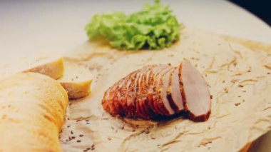 Fransız ekmeğiyle dilimlenmiş domuz filetosu. Sosis retro-stil yemek tepsisinde ve yemek kağıdında. Yavaş çekim kaydırağın üzerinde. Taze marul yaprakları da kullanıyoruz..