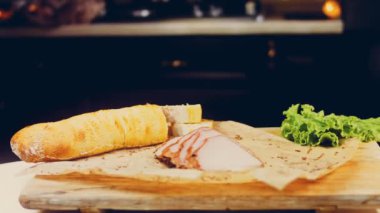 Fransız ekmeğiyle dilimlenmiş domuz filetosu. Sosis retro-stil yemek tepsisinde ve yemek kağıdında. Yavaş çekim kaydırağın üzerinde. Taze marul yaprakları da kullanıyoruz..