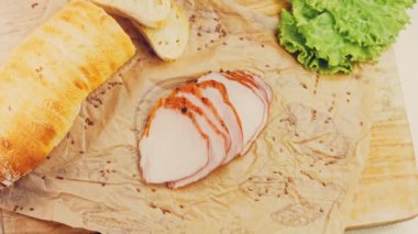 Fransız ekmeğiyle dilimlenmiş domuz filetosu. Sosis retro-stil yemek tepsisinde ve yemek kağıdında. Yavaş çekim kaydırağın üzerinde. Taze marul yaprakları da kullanıyoruz..