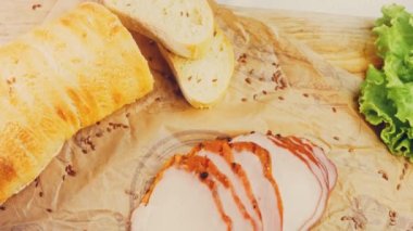 Fransız ekmeğiyle dilimlenmiş domuz filetosu. Sosis retro-stil yemek tepsisinde ve yemek kağıdında. Yavaş çekim kaydırağın üzerinde. Taze marul yaprakları da kullanıyoruz..